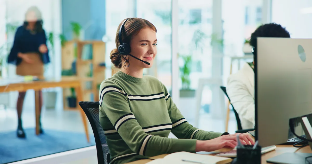 Medewerker met een headset achter haar scherm in een licht kantoor