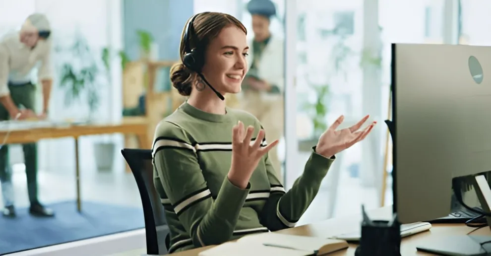 Medewerker met een headset praat met haar handen tijdens een gesprek achter haar scherm