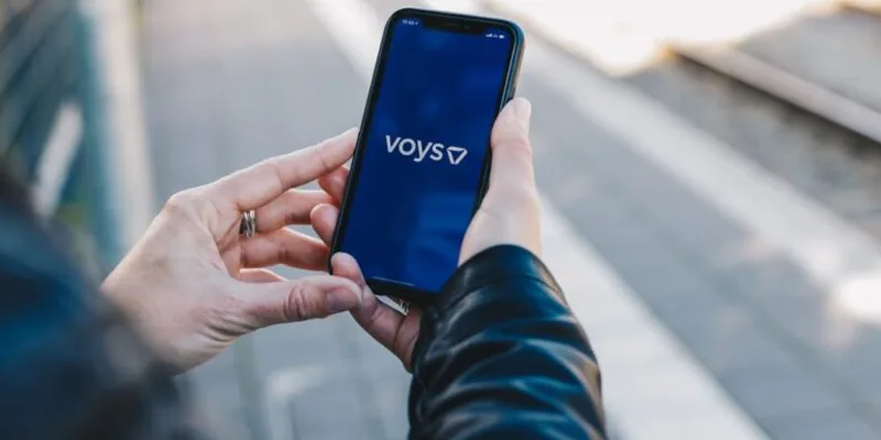 Hand met een telefoon waarop de Voys-app openstaat